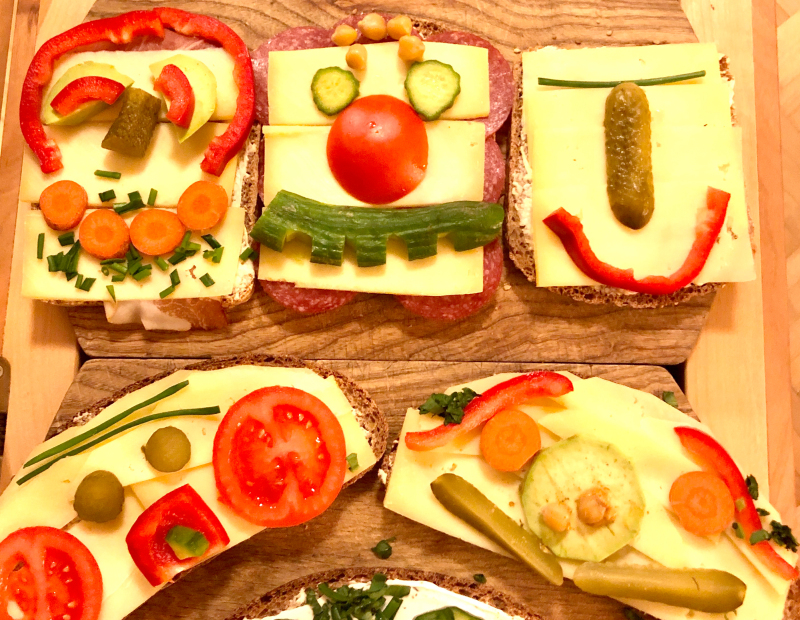 Gesichter aus Obst und Gemüse auf Brotscheiben