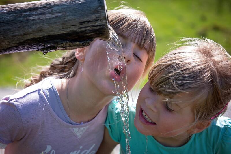 Kinder trinken am Brunnen