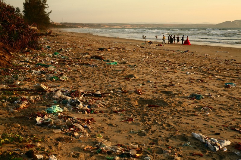 Plastikmüll am Strand, im Hintergrund das Meer