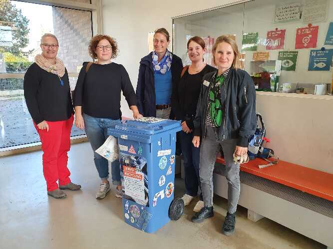 Ines Kayser, Kathrin Jung, Susanne Sigl, Kerstin Nafe und Judith Erb stehen vor dem Schaukasten der 17 SDG's und einer Jeansrecyclingtonne