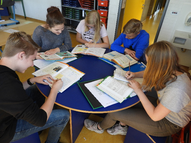 Das Bild zeigt Schülerinnen und Schüler an einem runden Tisch.