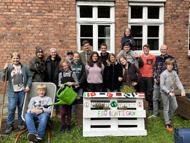 Ein Gruppenbild vom ESGrün-Team im Schulgarten mit einem Upcycling-Projekt
