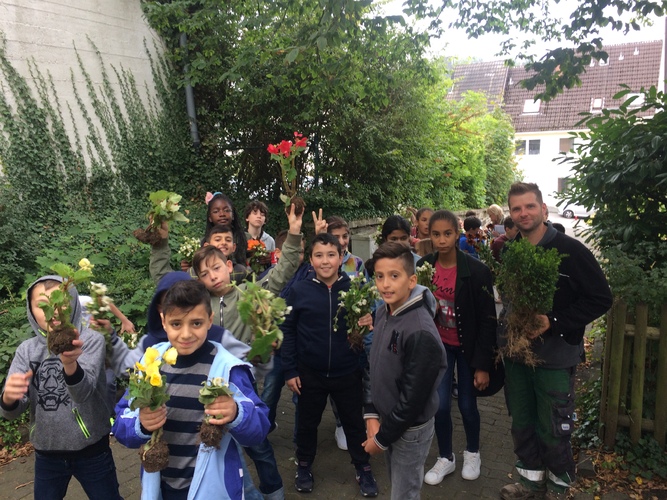 Die Schüler*innen der Realschule Am Oberen Schloss erhalten Blumen von den Stadtgärtnern und pflanzen diese auf dem Schulgelände wieder ein.