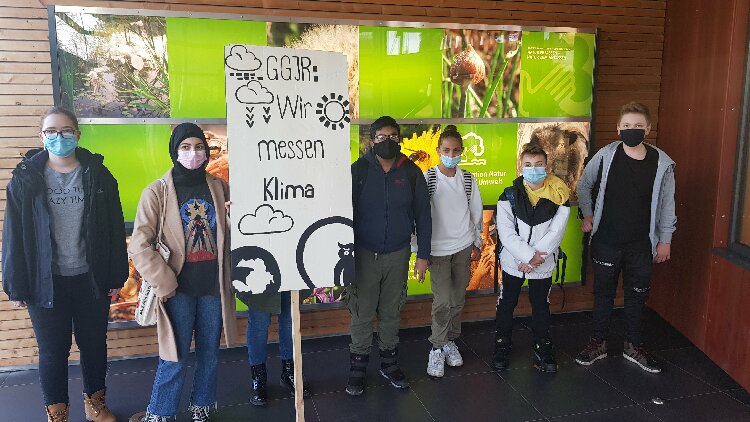 Schülergruppe und Schulleiter posieren im Eingang unseres Kooperationspartners Station Natur und Umwelt