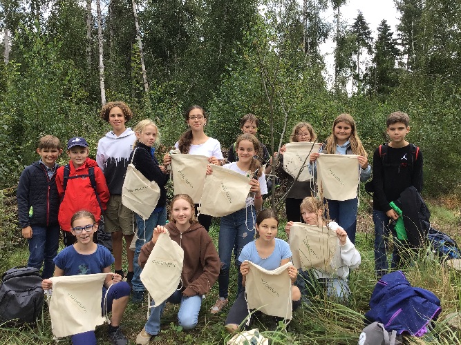 Schüler*innen nach einem Arbeitseinsatz auf unserer Aktionsfläche im Wald, beschenkt mit Leinenbeuteln mit der Aufschrift 