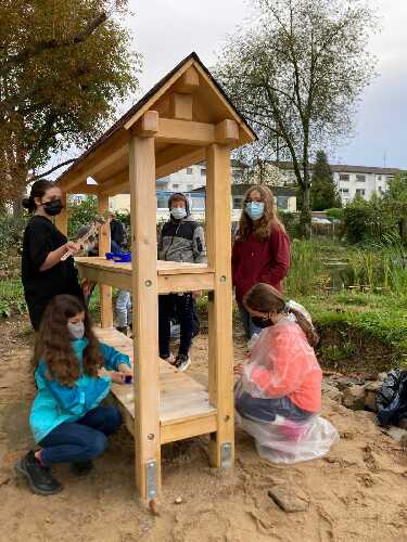 Das Foto zeigt Schülerinnen und Schüler, die das neue Insektenhotel streichench befreien