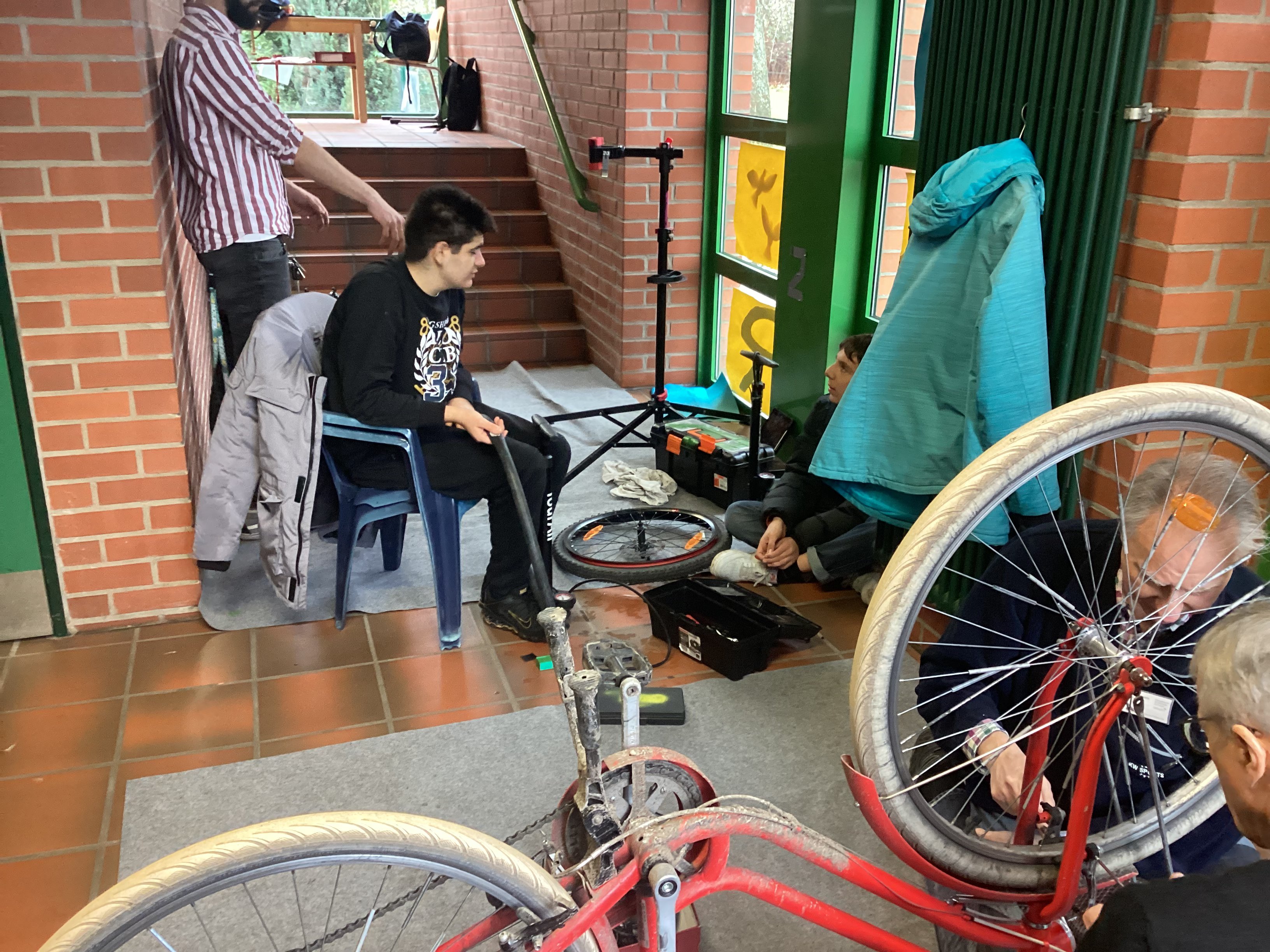 Zwei Schüler, Herr Heitmann und die ehrenamtlichen Helfer reparieren Fahrräder.