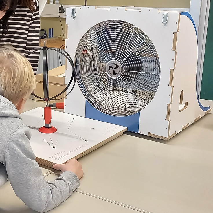 Das Bild zeigt ein Kind beim Experimentieren mit dem Windexperimentierkoffer