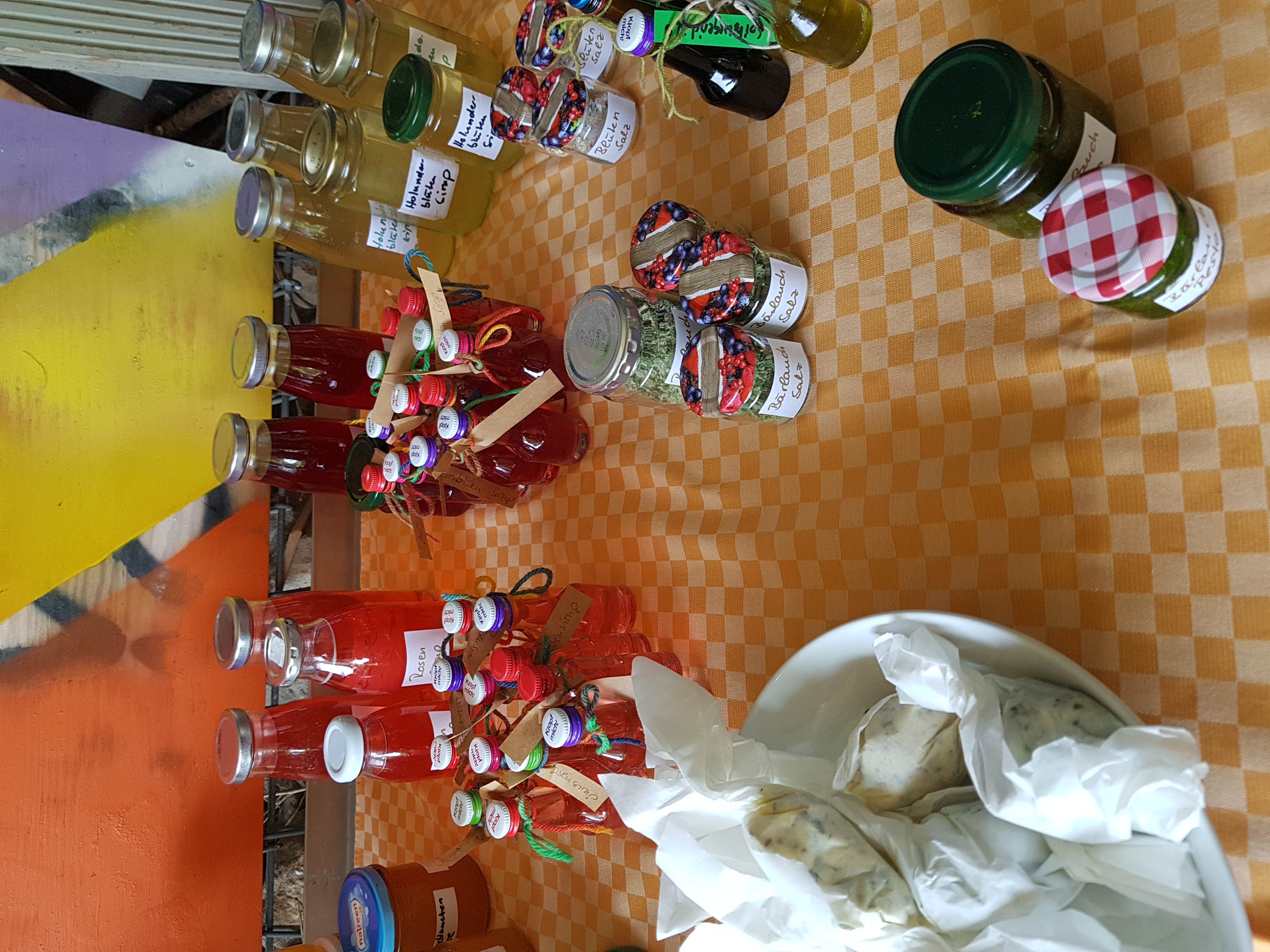 Auf dem Bild sind unsere verschiedenen Sirups, Salze, Pesto und Buttervariationen in kleinen Flaschen und Gläschen zu sehen.