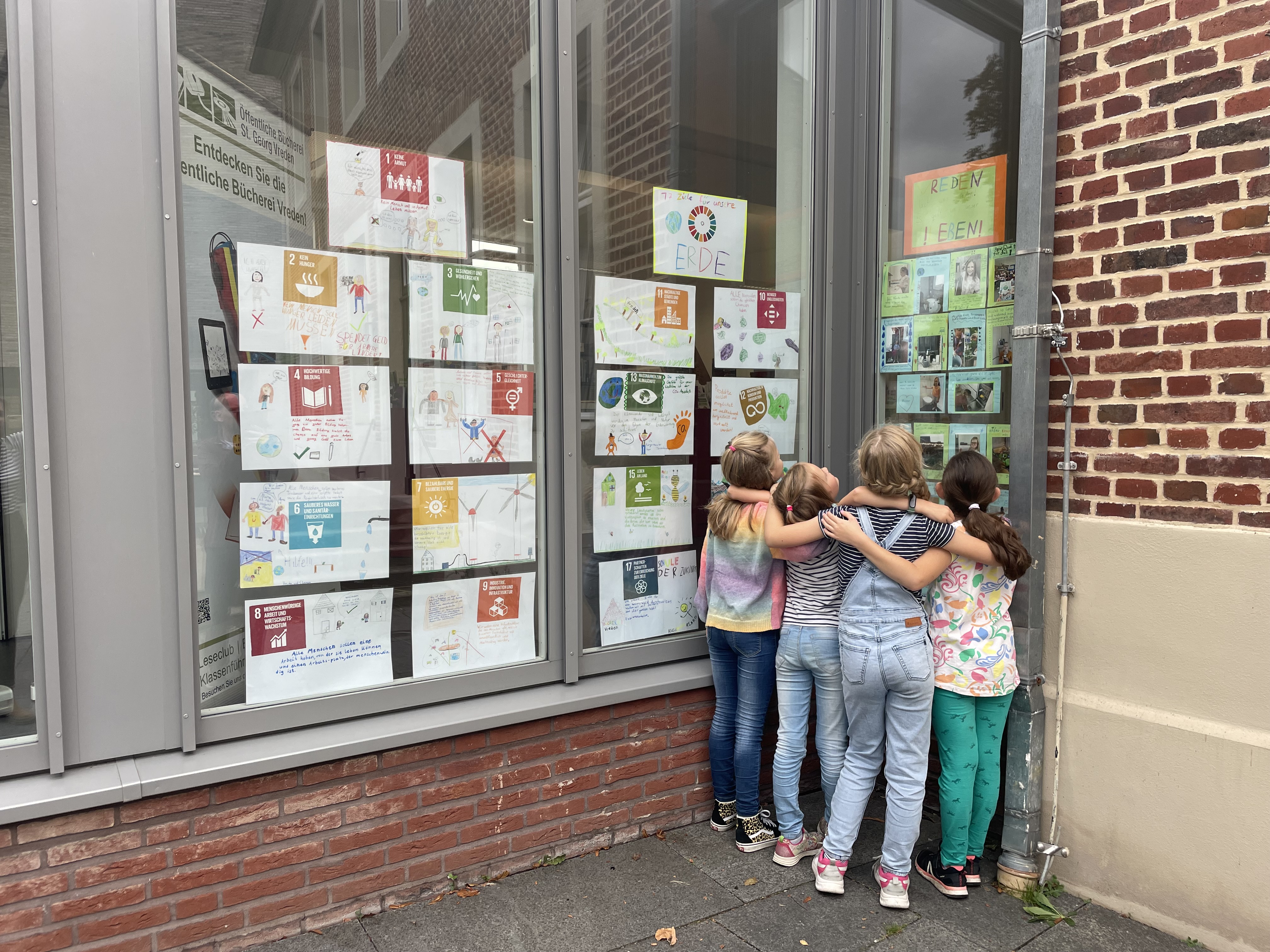 Eine Gruppe Kinder betrachtet ihr Werk- eine Ausstellung zu den 17 Zielen und Ideen und Tipps für eine bessere Welt.