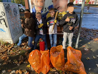4 Schüler zeigen stolz ihre Funde und die gefüllten Mülltüten nach der Müllsammelaktion