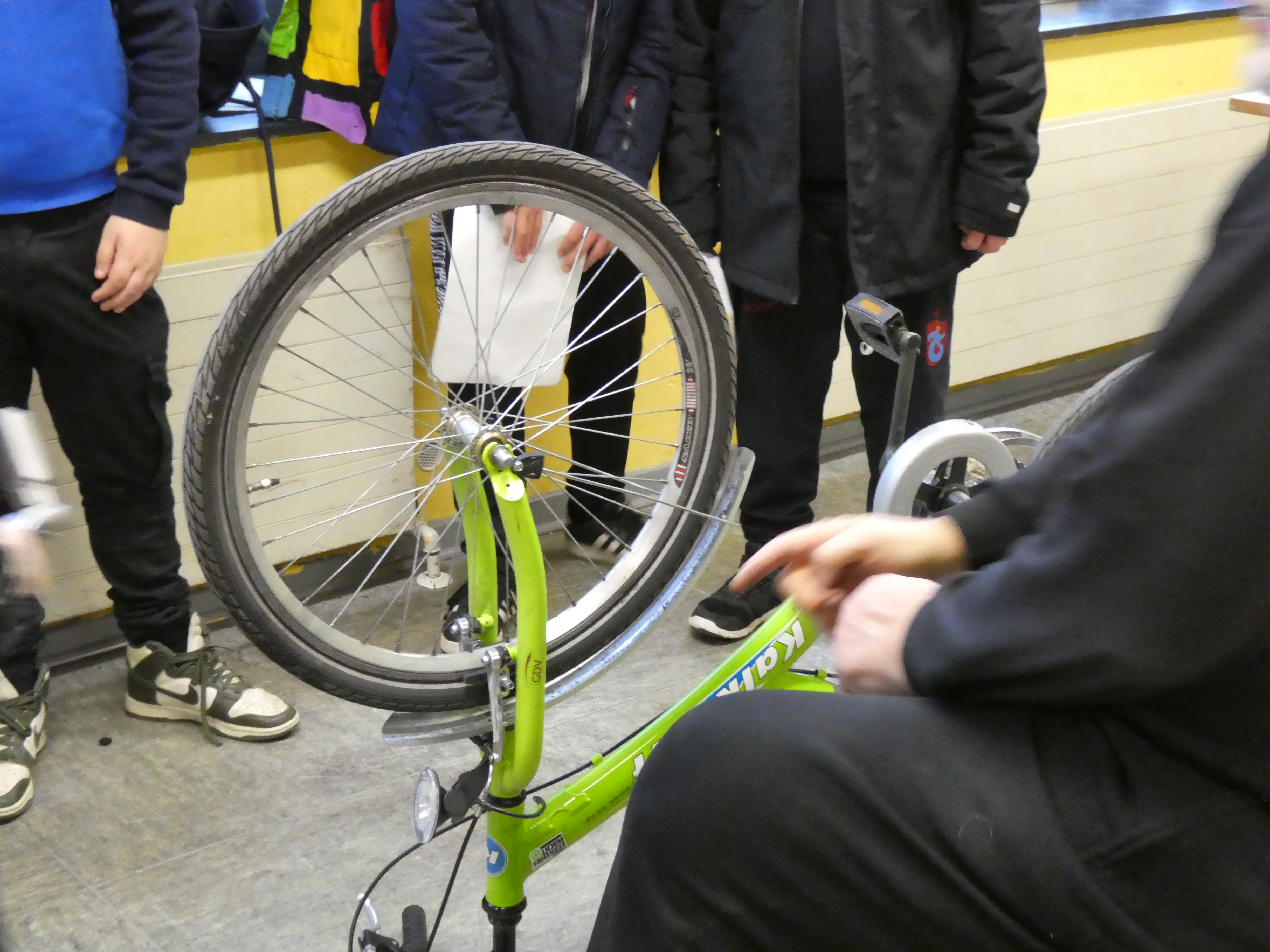 Ein  grünes Fahrrad steht auf seinem Lenker, damit das Vorderrad ausgebaut werden kann.