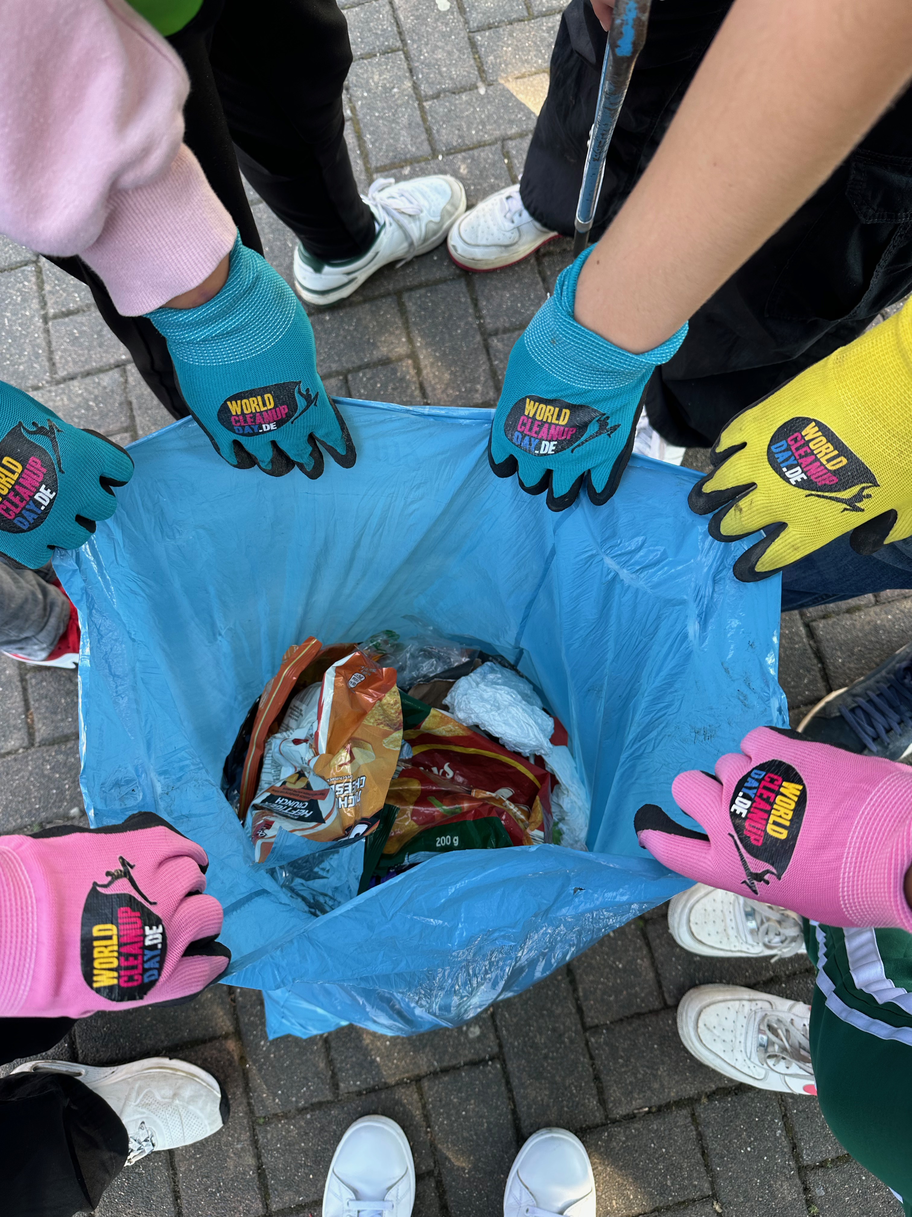 Schülerinnen und Schüler verdeutlichen mit ihrem Müllsack, dass in kurzer Zeit eine beachtliche Menge Müll gesammelt wurde. 