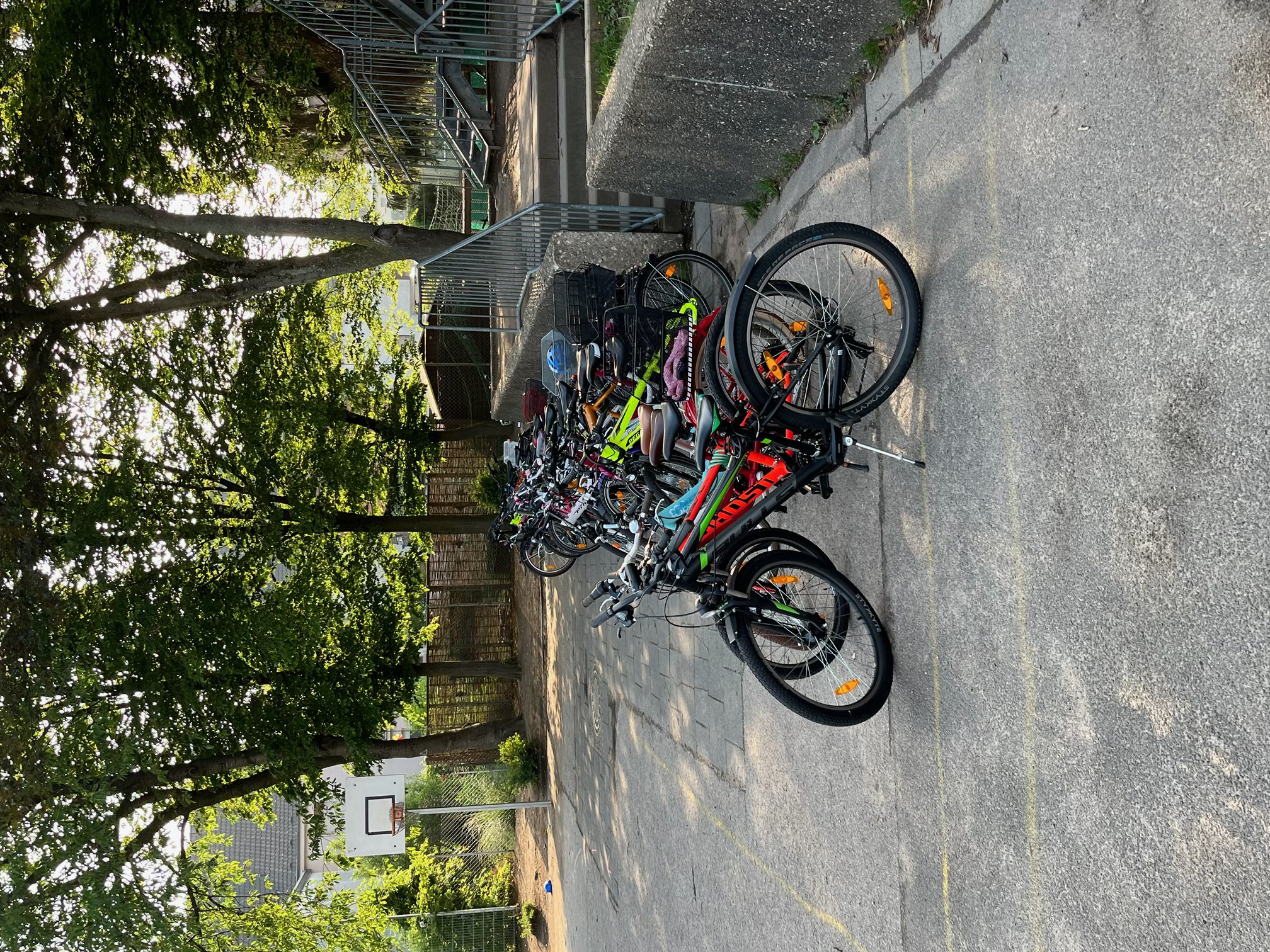 Die Kinderfahrräder stehen hintereinander auf dem Schulhof