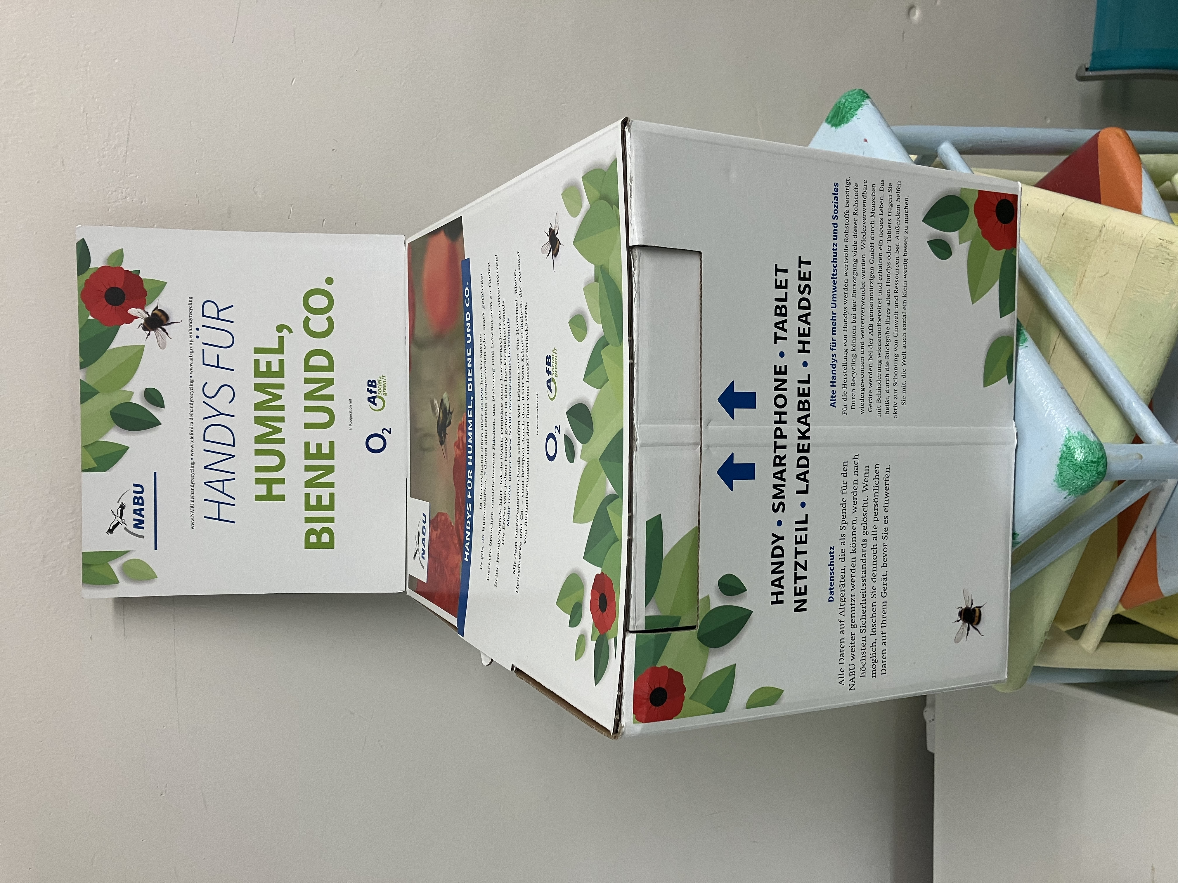 Eine Sammelbox aus weißem Karton mit grünem Schriftzug 
