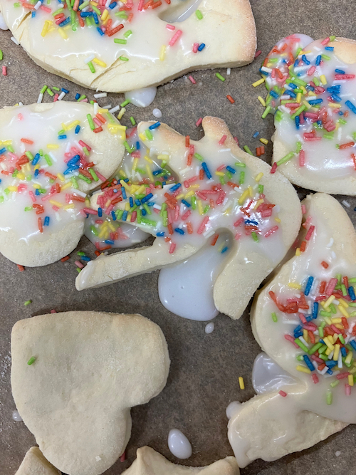 Das Bild zeigt Kekse in deren Mitte ein Keks die  Form einer Vogelhand, dem Logo der Menschenrechte hat.  Die Kekse sind mit weißen Zuckerguss bestrichen und mit bunten Streuseln verziert. 