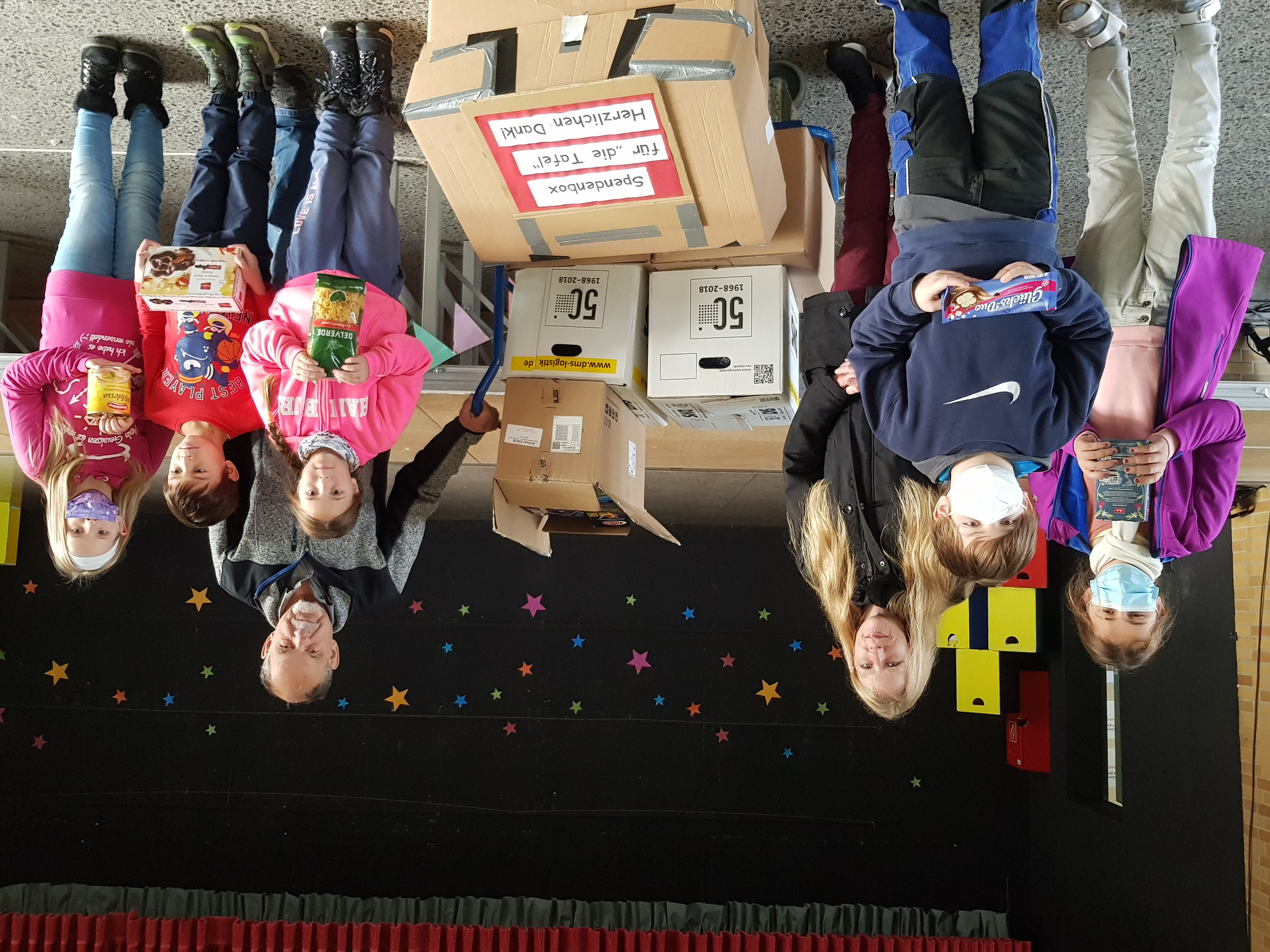 Kindergruppe übergibt Kartons mit haltbaren Lebensmitteln an Vertreter der Tafel