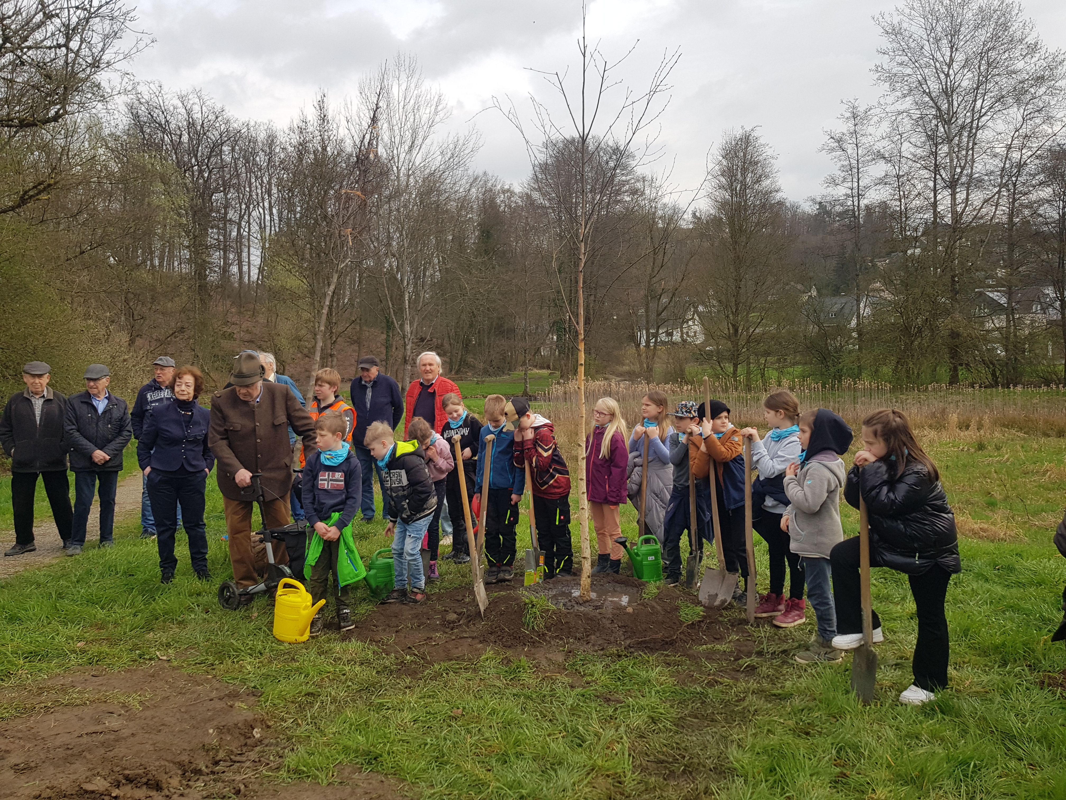Kindergruppe pflanzt mit Gärtern Baum ein