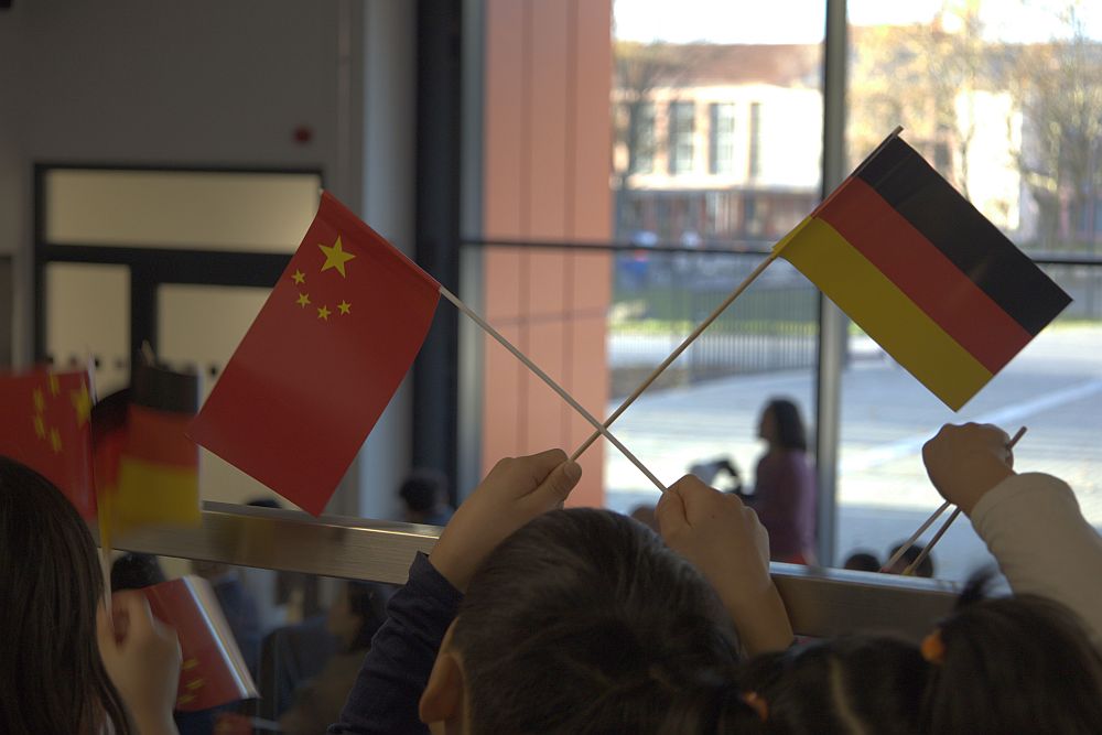 Schüler schwenken auf der Empore der Aula deutsche und chinesische Papierfähnchen während der Feier. 