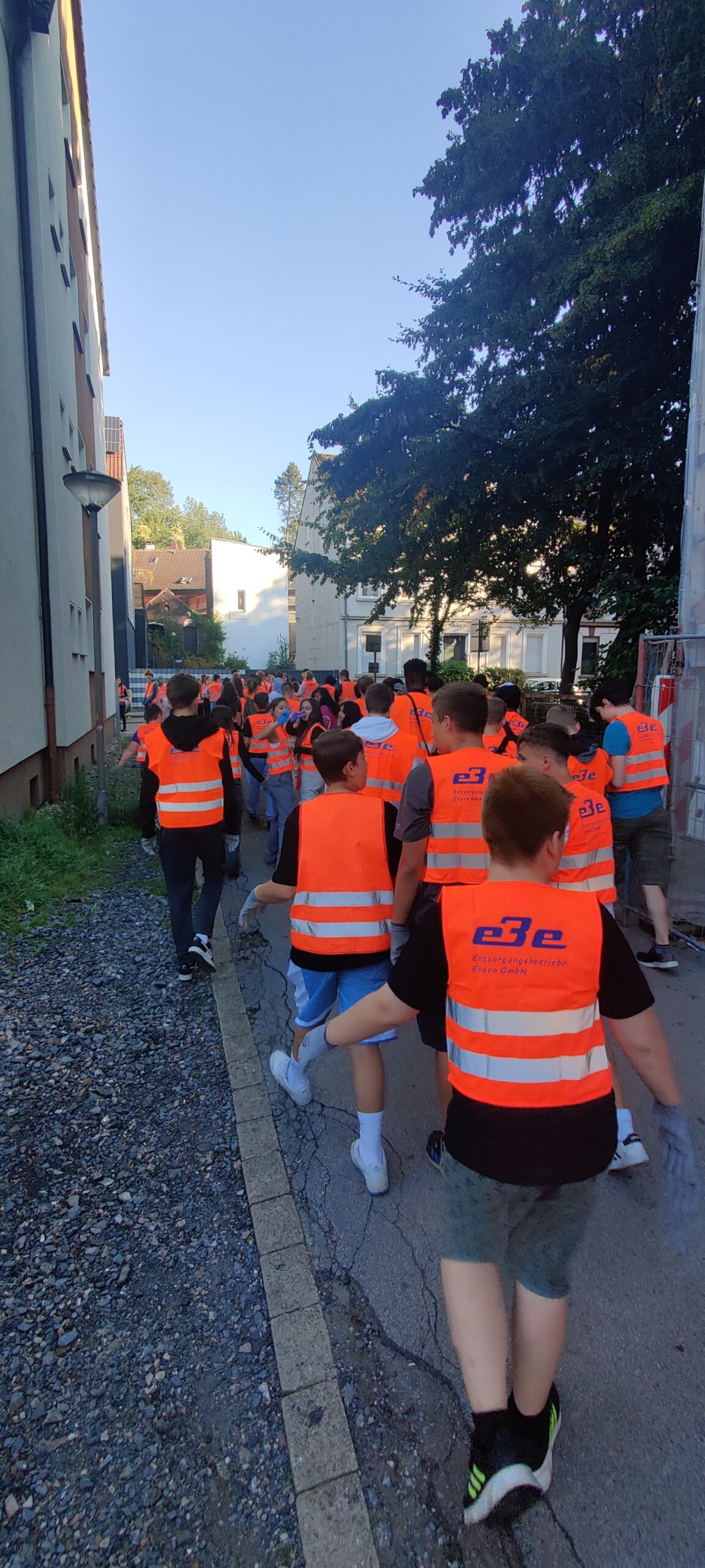 Schülerinnen und Schüler, alle bekleidet mit roten Warnwesten,  sind zu Fuß unterwegs zur Ruhr.