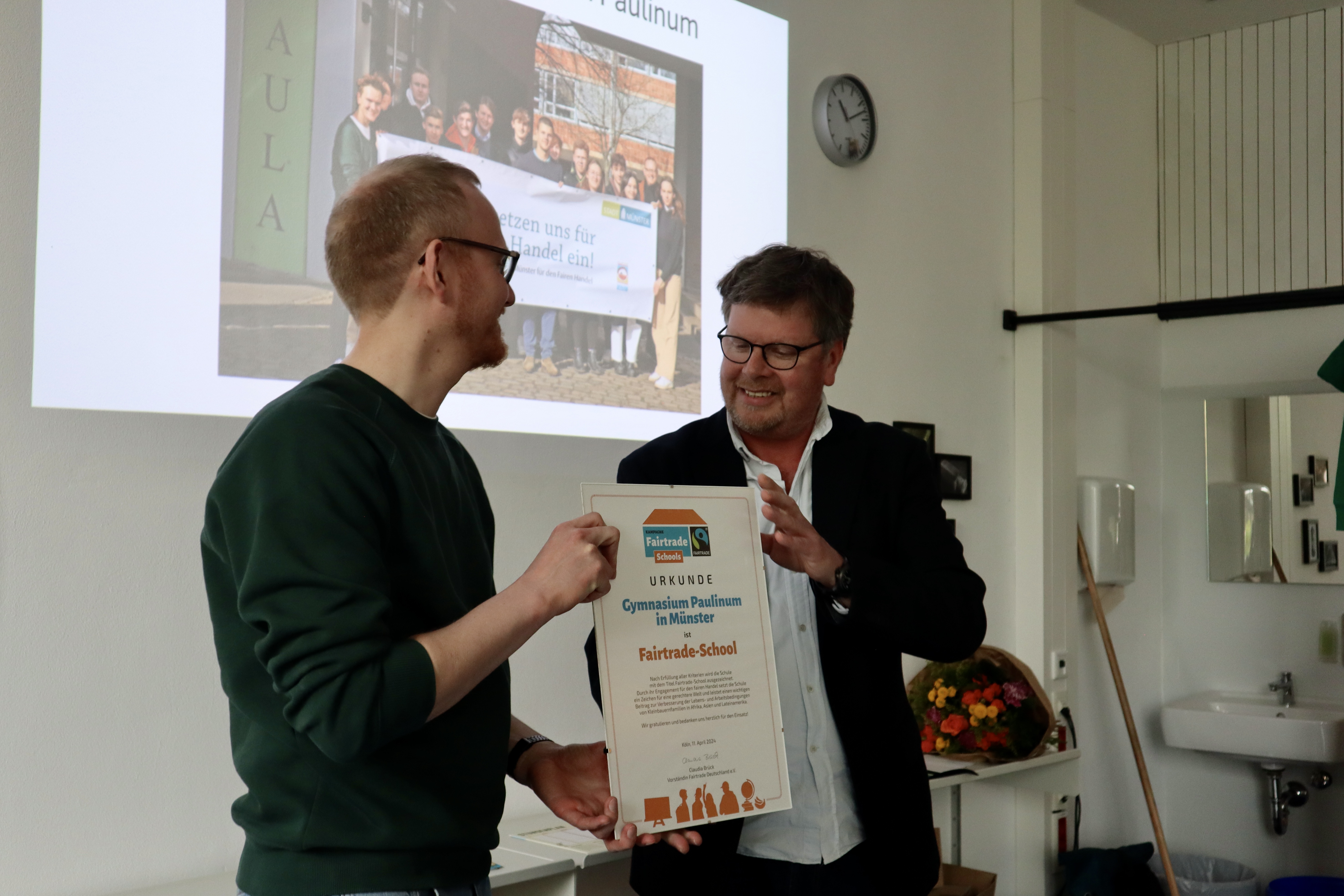 Herr Elkmann überreicht die Urkunde an Herrn Bruns aus der Fairtrade-Gruppe des Gymnasium Paulinum